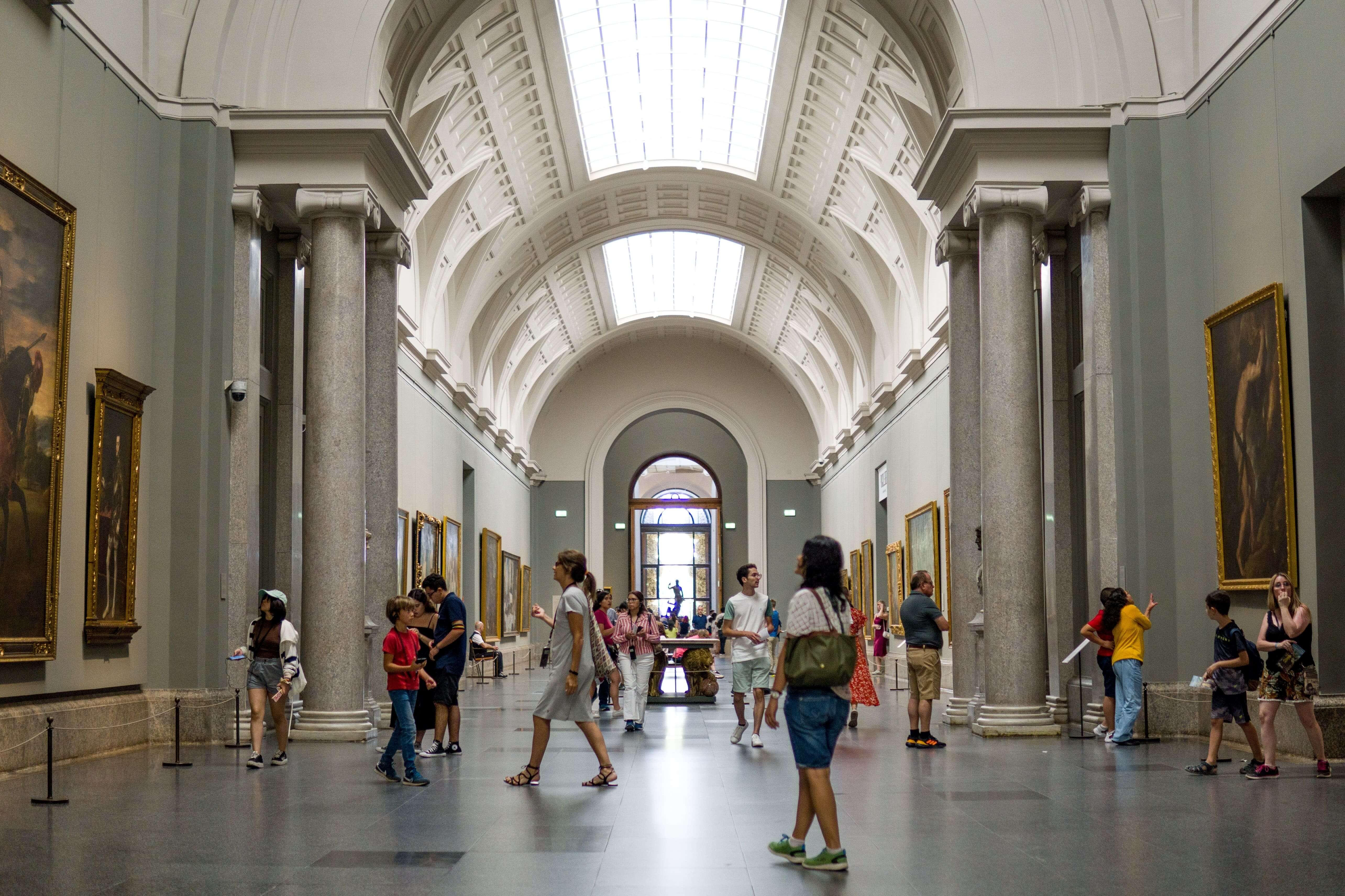 Tourists Wandering Through the Central Corridor of the Prado Museum Observing Famous Paintings in Madrid, Spain.